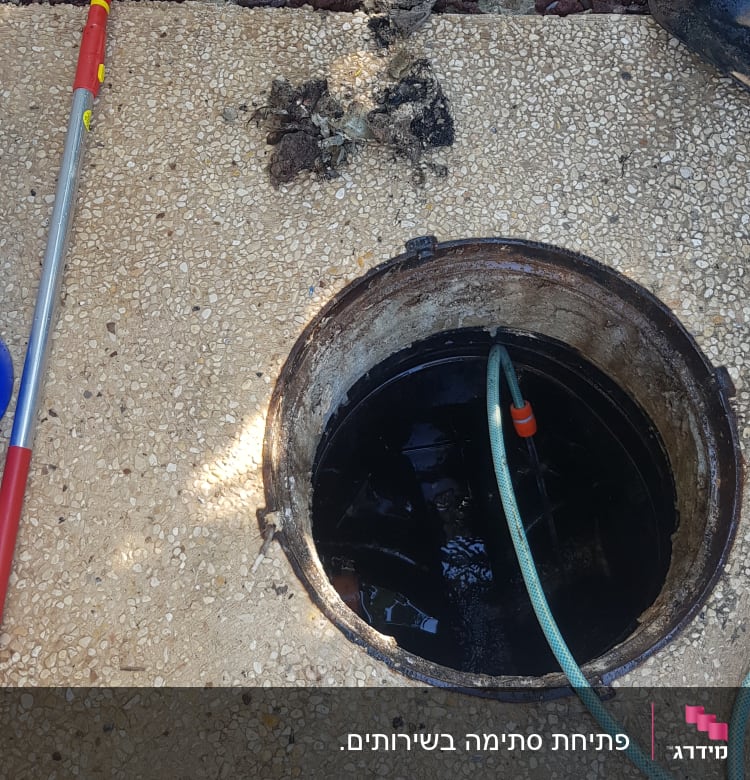 פתח ביוב עם צינור מים וכלי עבודה